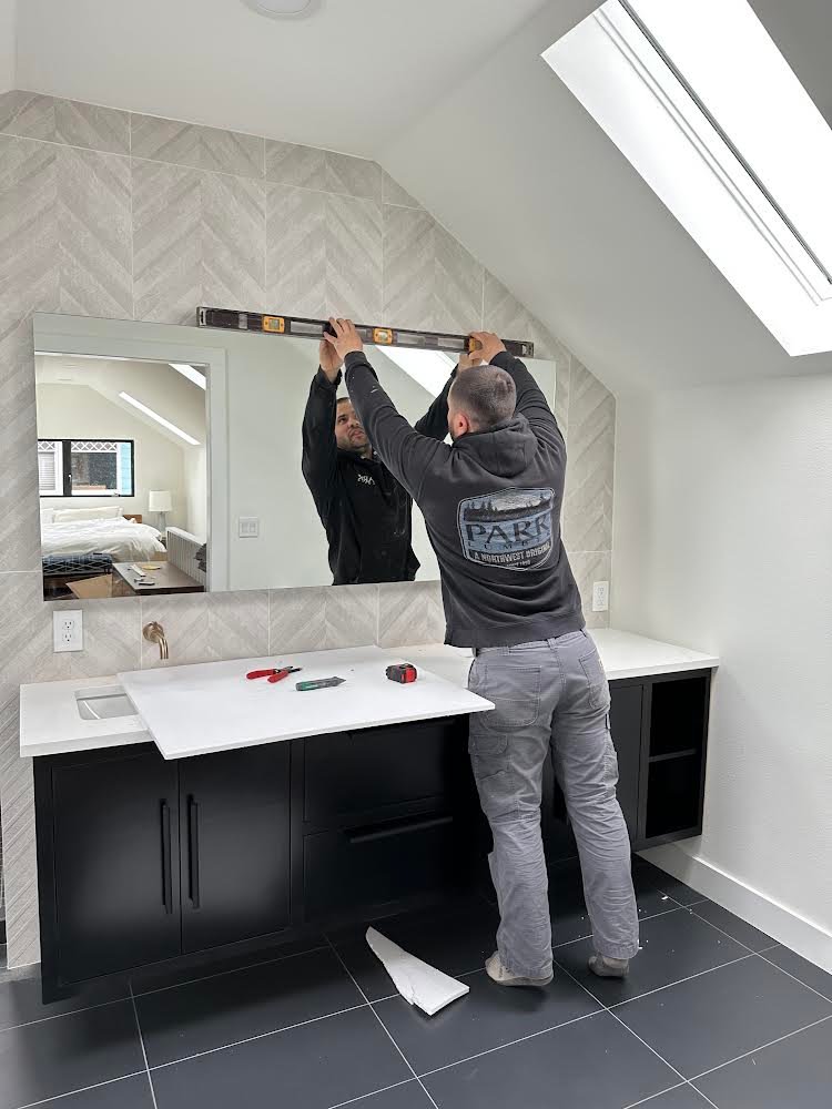 Dmitiry leveling a mirror in a bathroom